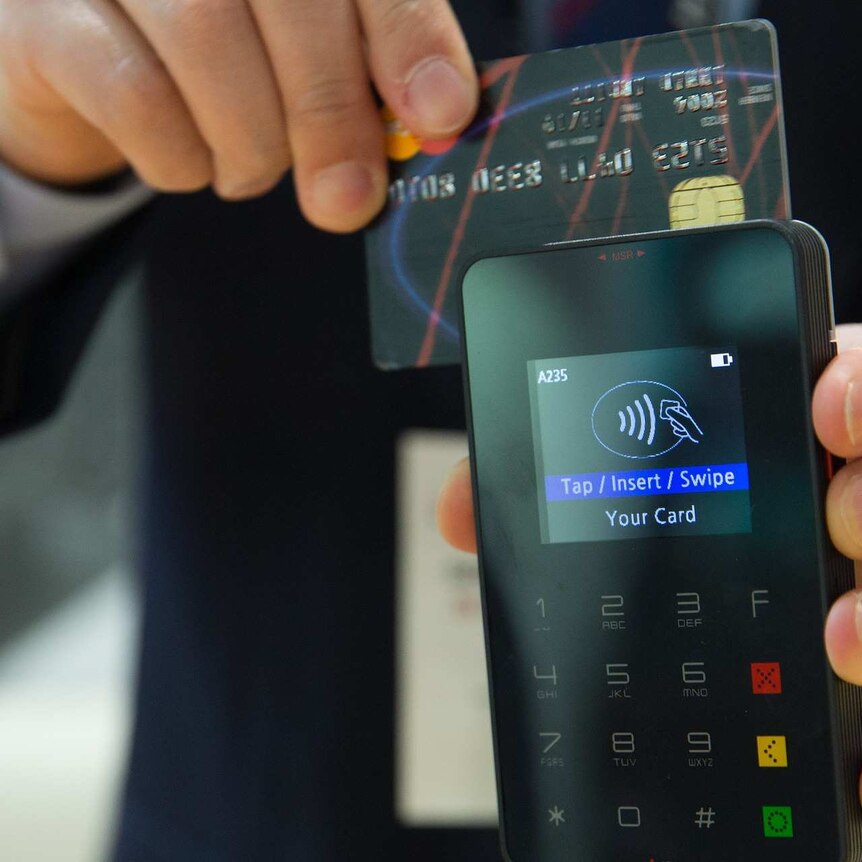 A hand holding a credit card in an EFTPOS machine