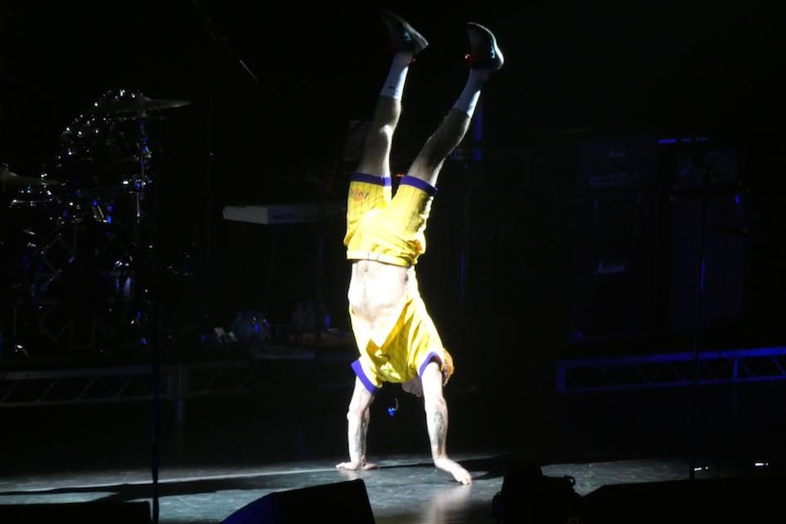 Red Hot Chili Peppers' Flea handstands for the crowd during a power outage in Hobart.