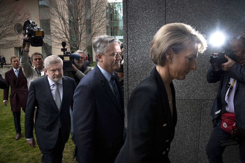 Mitch Fifield, Mathias Cormann, Michaelia Cash walk from a large media pack