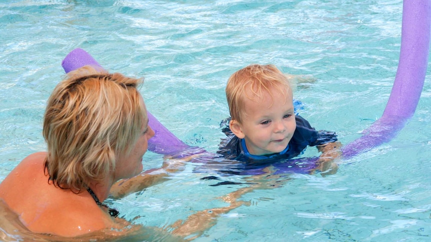 A mother and son swimming in a backyard pool