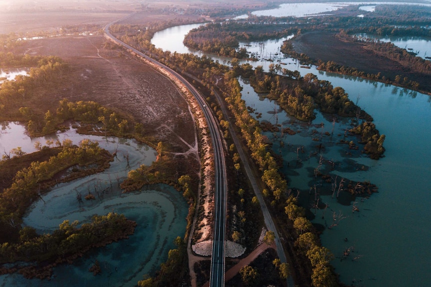 Drone view over a meandering river and a winding road