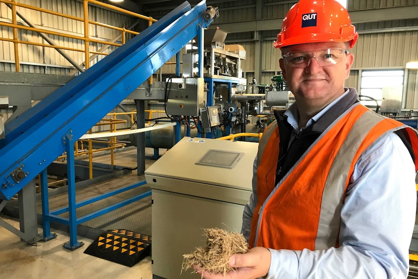 A man holding a material called bagasse that looks similar to hay