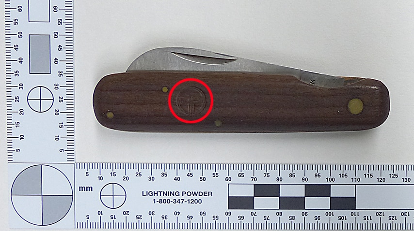 A pocket knife next to a ruler, with a faint Telecom logo embossed on it.