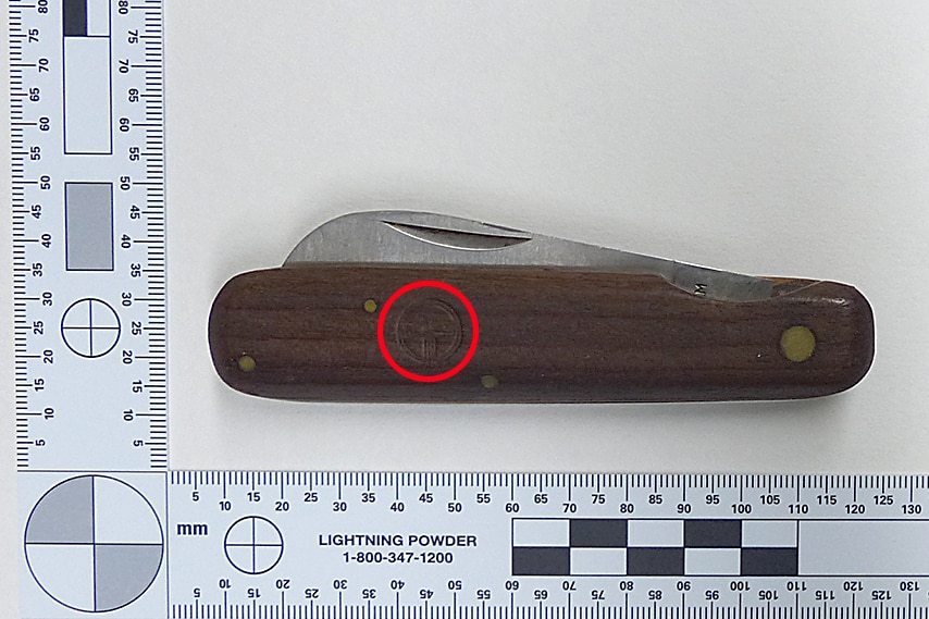A pocket knife next to a ruler, with a faint Telecom logo embossed on it.