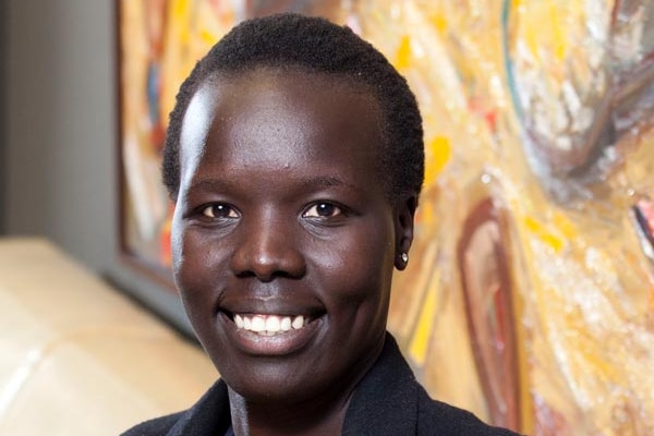 A profile photo Nyadol Nyuon looking straight into the camera and smiling.