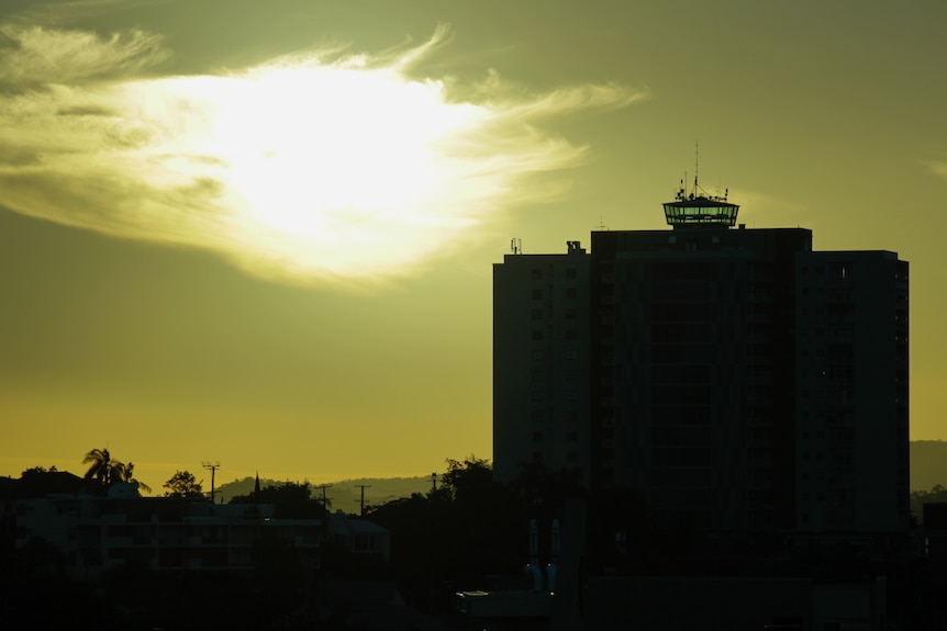 The silhouette of an apartment complex with the setting sun in the background 