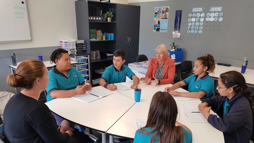 Students and teachers at Woodville Gardens School sit around a table.