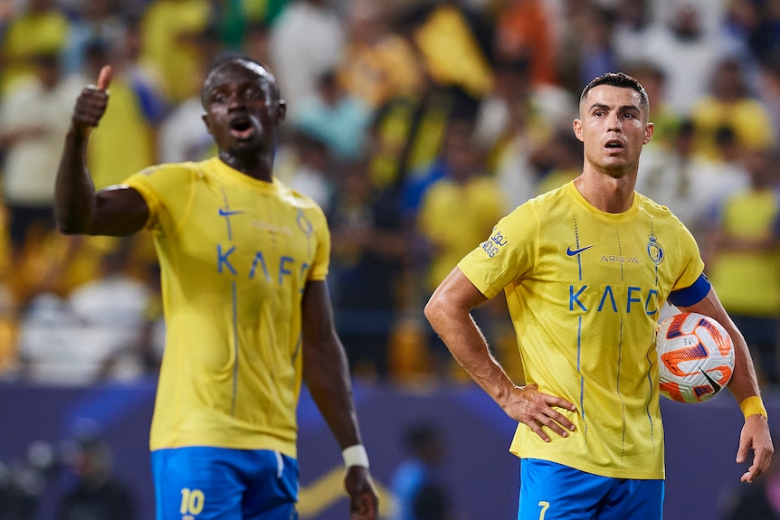 Sadio Mane signals and Cristiano Ronaldo holds a ball during a Saudi Pro League game for Al-Nassr FC.