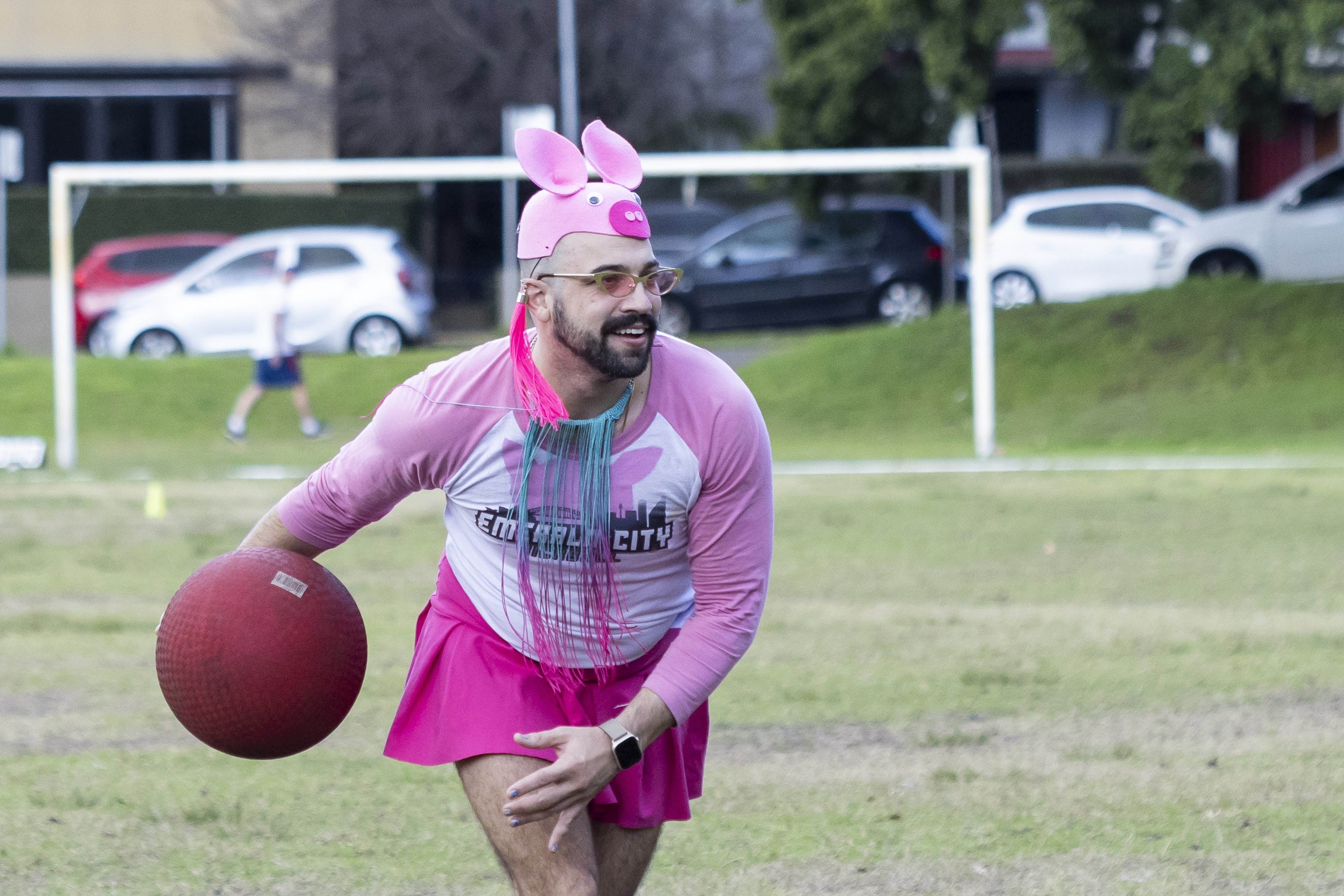 A man in pink and a pig hat gets ready to throw a ball