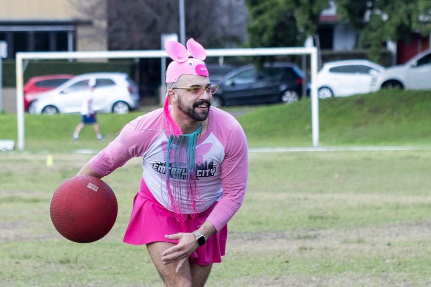 A man in pink and a pig hat prepares to throw the ball