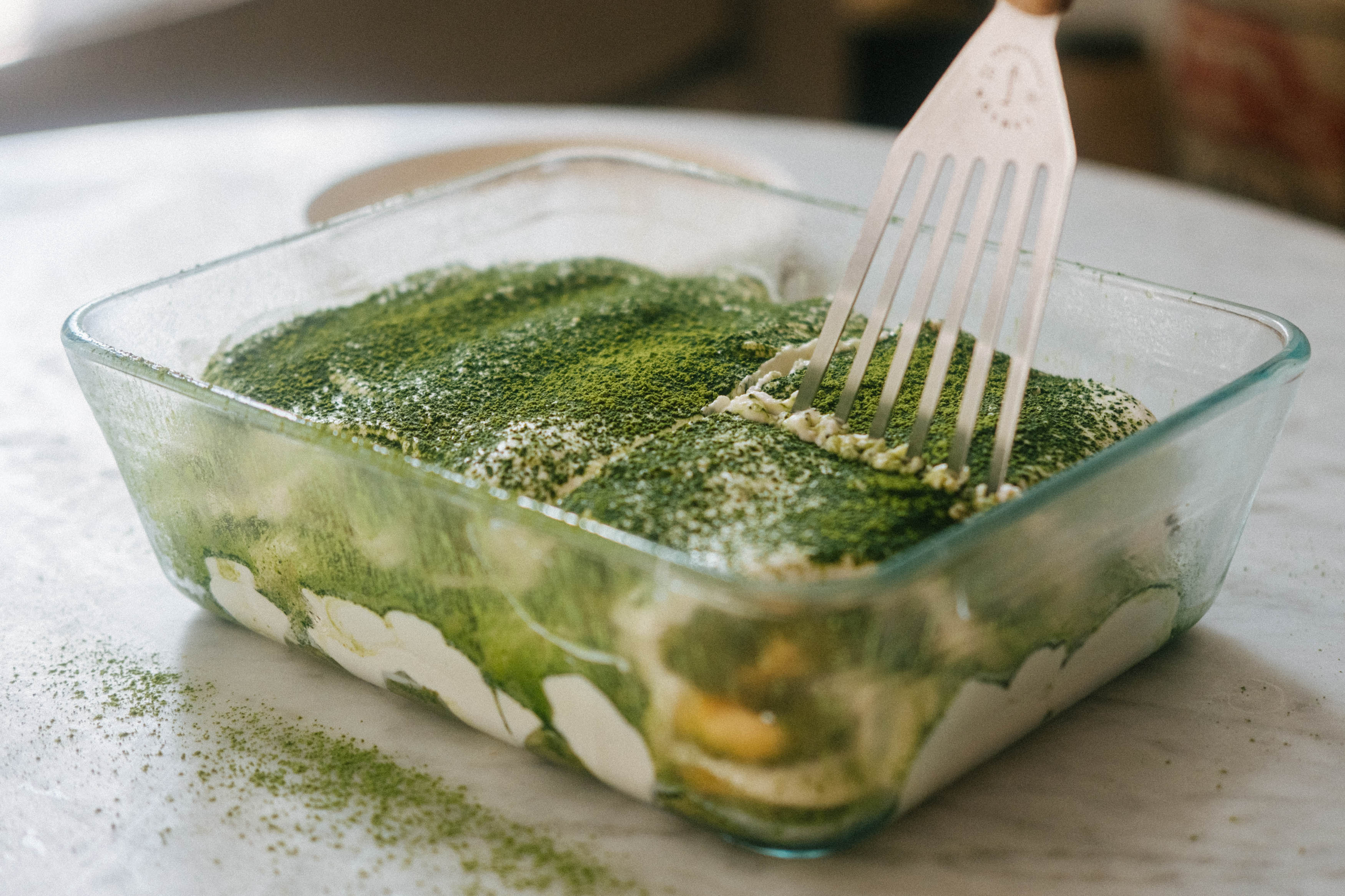 A spatula digs into a matcha tiramisu, a summer dessert for Christmas.