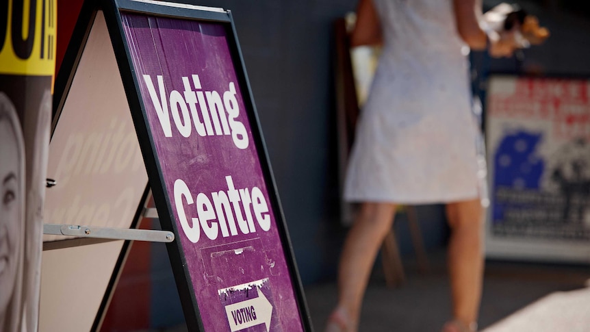 A purple sign with white writing on an a frame says 'voting centre' with an arrow that says 'voting'