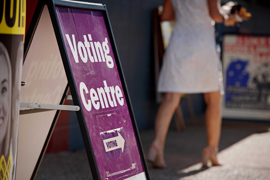 A purple sign with white writing on an a frame says 'voting centre' with an arrow that says 'voting'