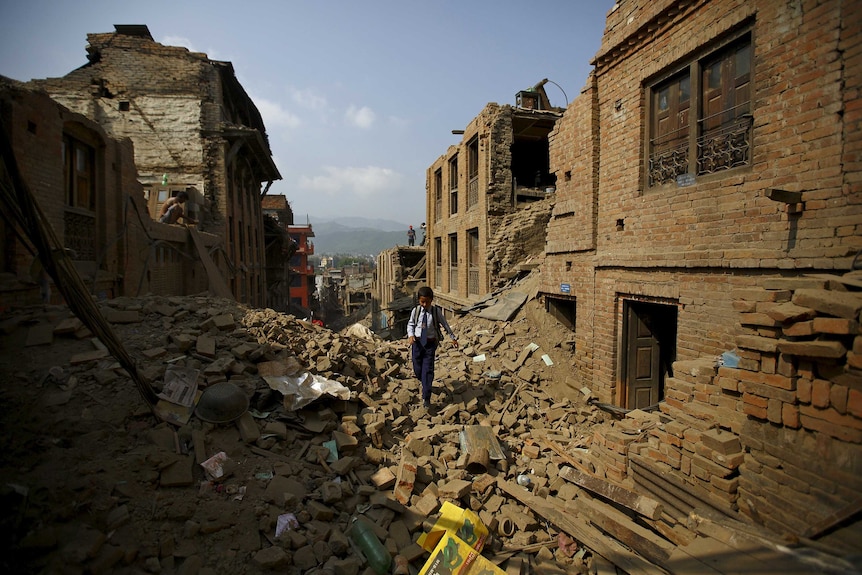 Nepalese child walks to school through rubble