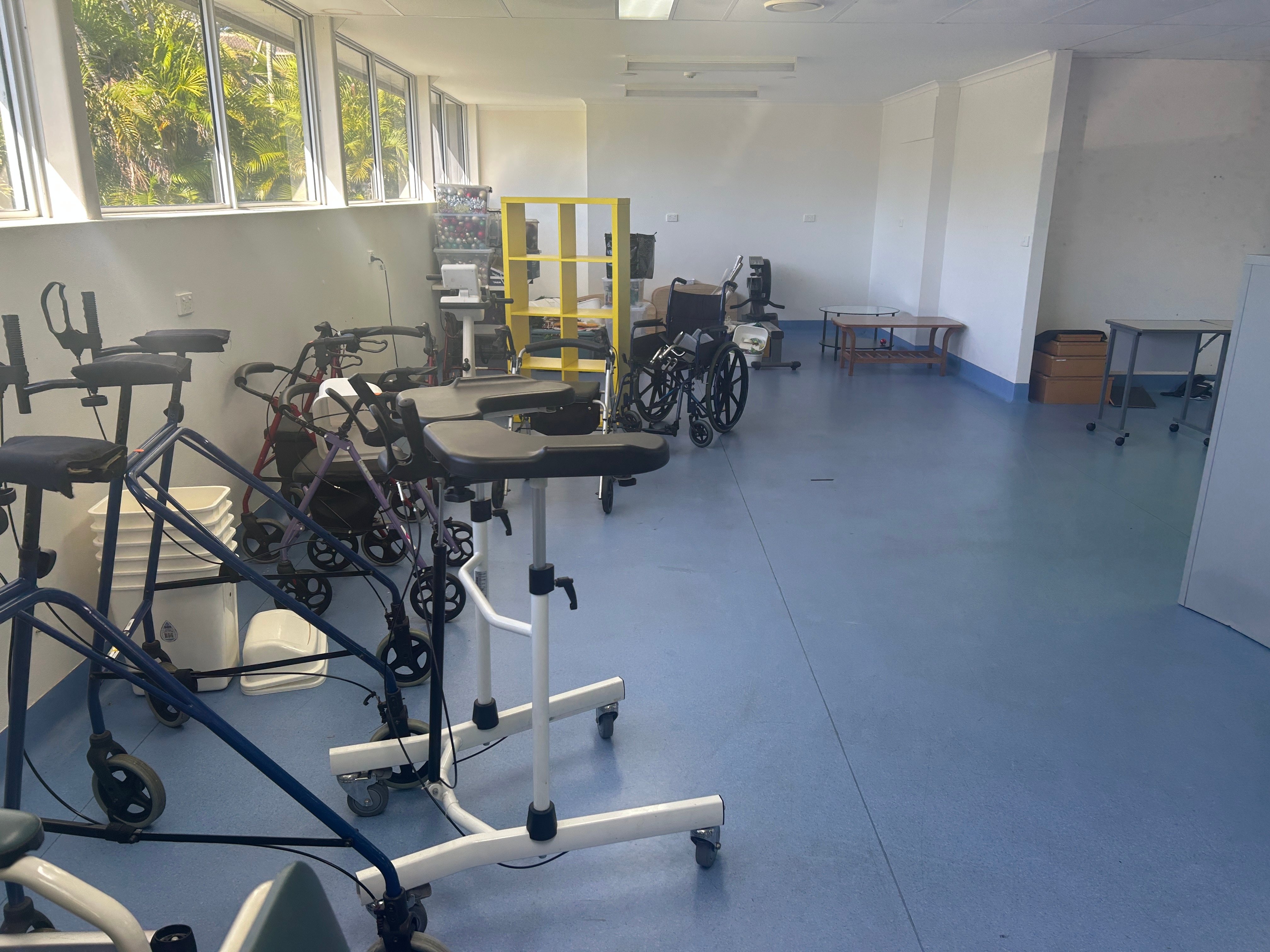 A room with walkers, wheelchairs and bins scattered around it