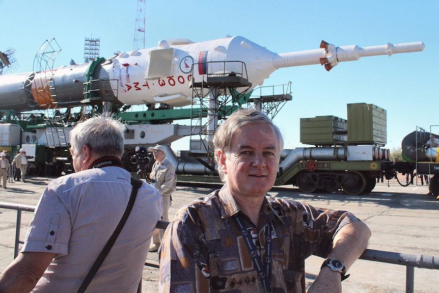 Man stands in front of large white rocket