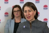 Two women standing in front of a board with NSW logos.