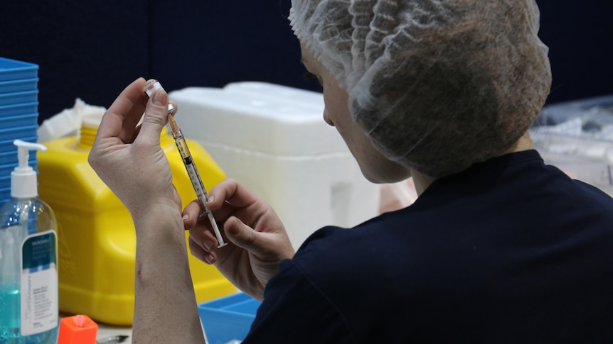 A woman prepares a pfizer vaccine shot in Perth