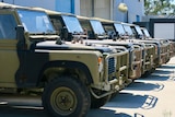 A line of land rover perenties parked at the Australian frontline machinery site, all cars are camouflaged 