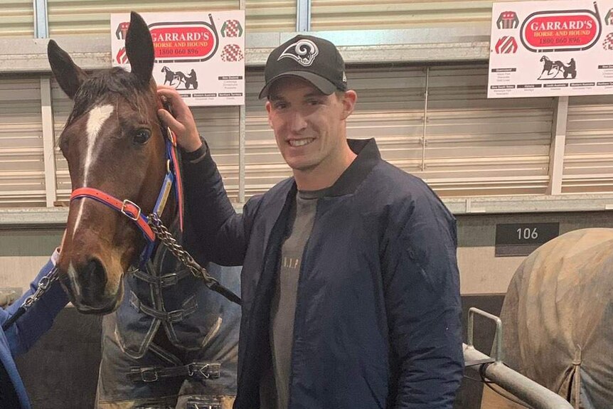 Josh Jenkins standing next to a harness racing horse.