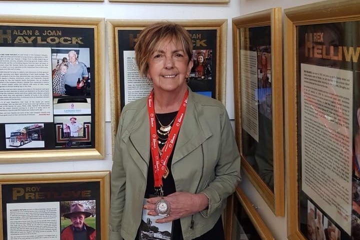 Maralyn standing in front of pictures in the Hall of Fame.