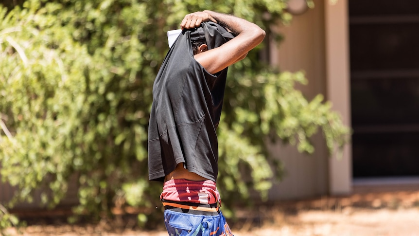 A man covers his face after walking out of a court hearing.  