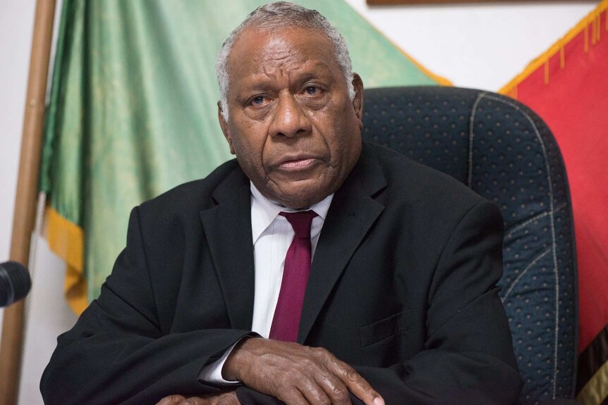 Vanuatu's late President Baldwin Lonsdale sitting in an office giving a press conference.