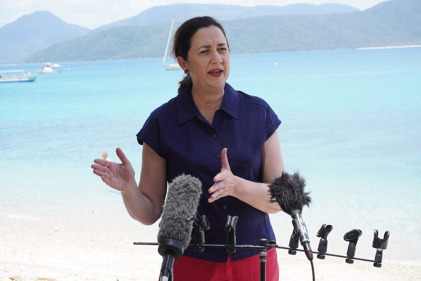 Annastacia Palaszczuk speaks at a press conference on Fitzroy Island, off Cairns, with ocean behind her.