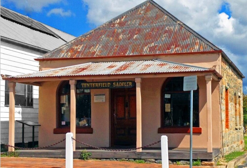 A clay coloured hertiage building with the sign Tenterfield Saddler above the balcony.