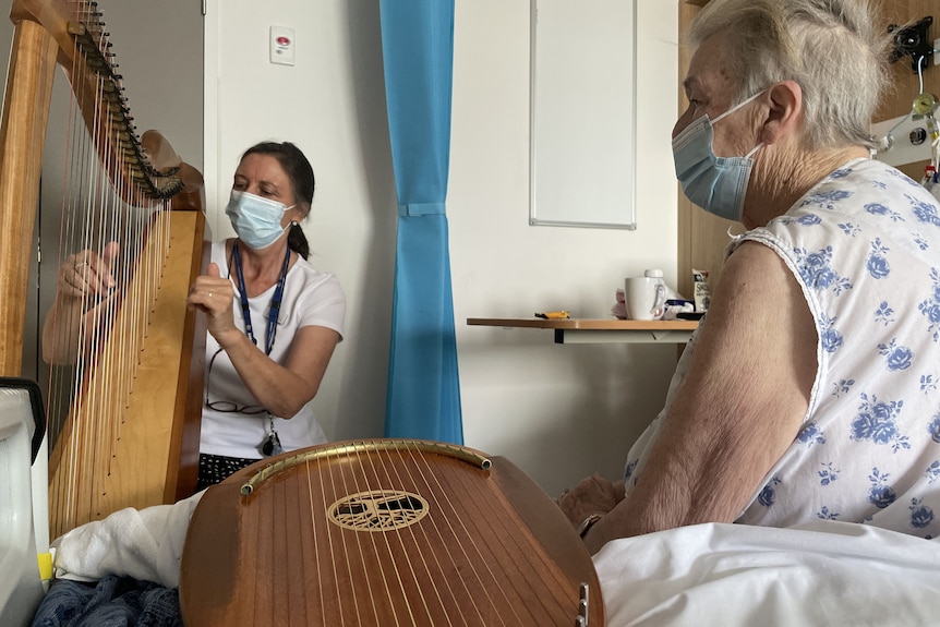 Music therapist Alison Ware plays the harp for a patient.