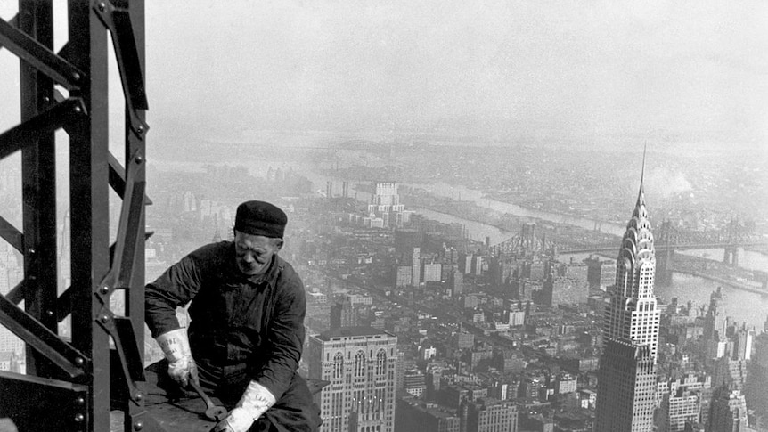 A worker on the Empire State Building with the Chrysler Building in the background