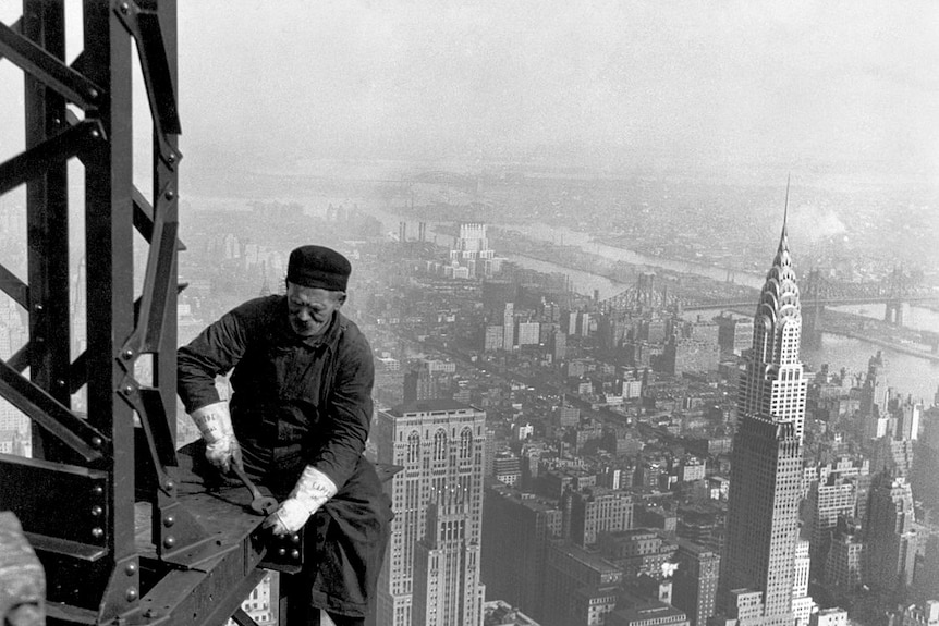 A worker on the Empire State Building with the Chrysler Building in the background