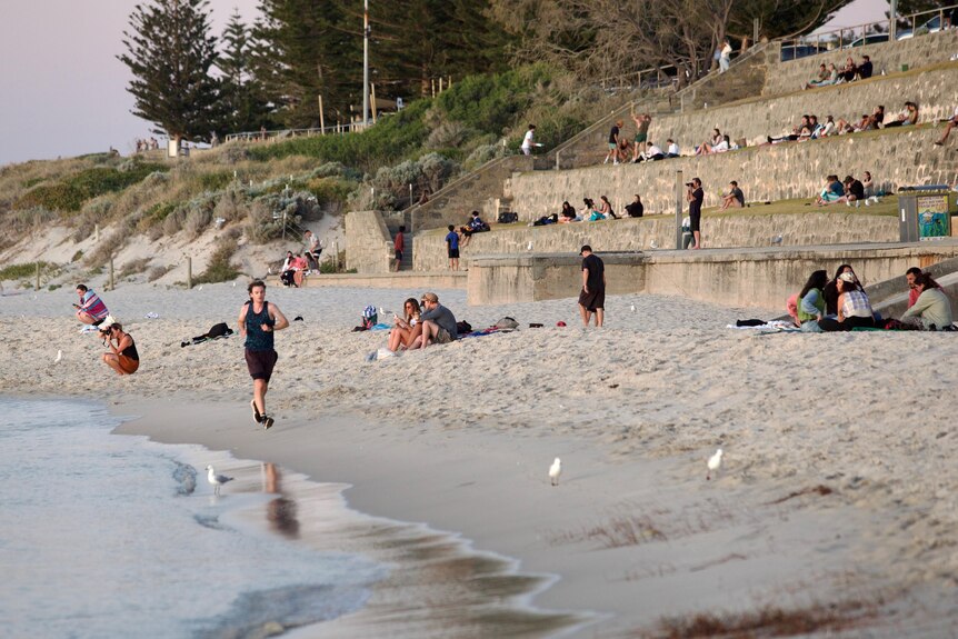 People sitting and running on Cottesloe Beach