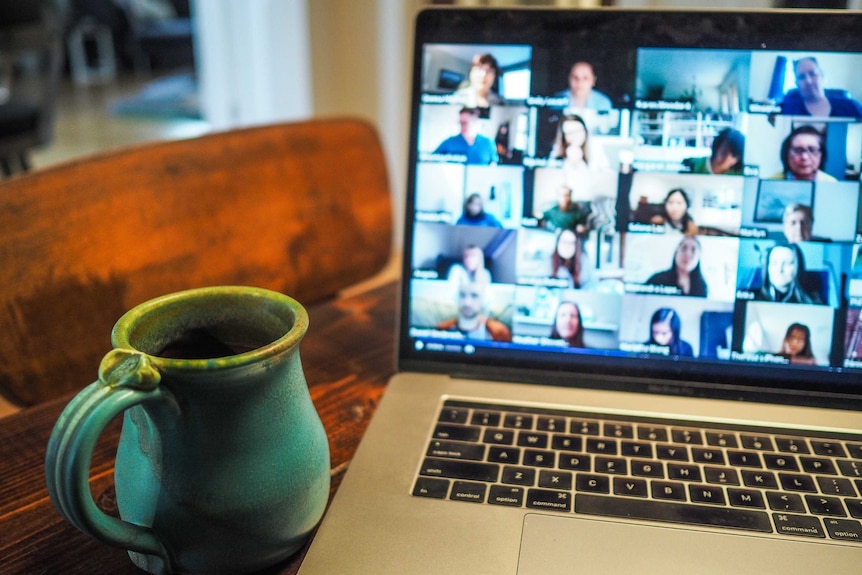 A laptop screen shows a video conference call in progress.