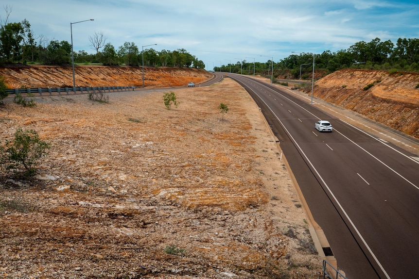 A two lane highway cut through red rock. No landscaping.