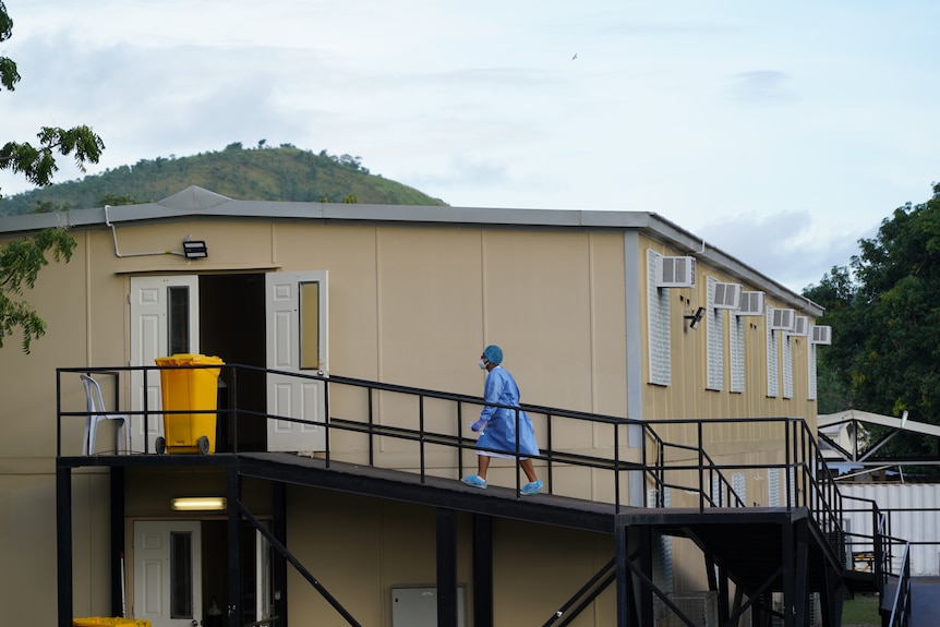 A person wearing a gown and mask walks into a building.