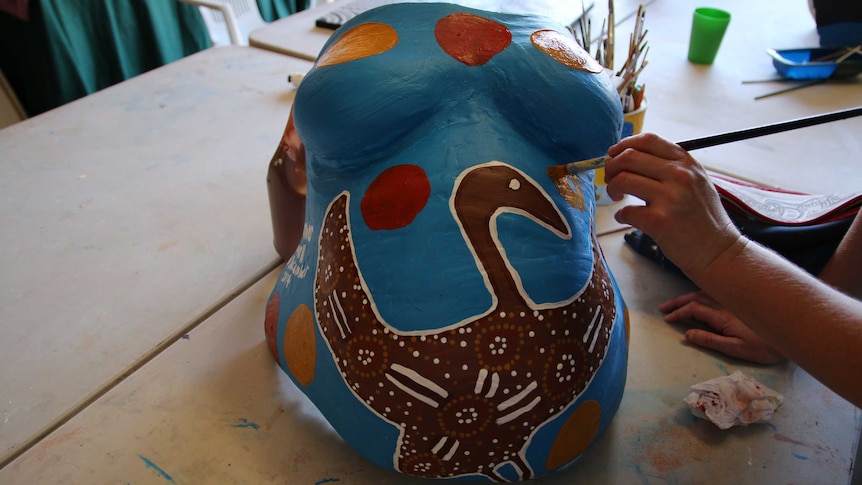 A woman paints a life-size plaster cast of her belly at the Gomeroi gaaynggal centre in Tamworth.