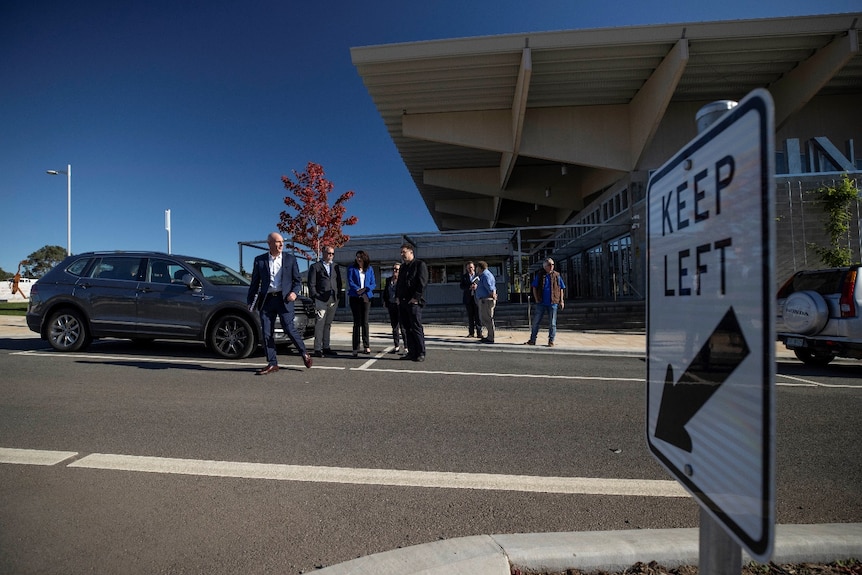 A bald man crosses the road with a group of other people