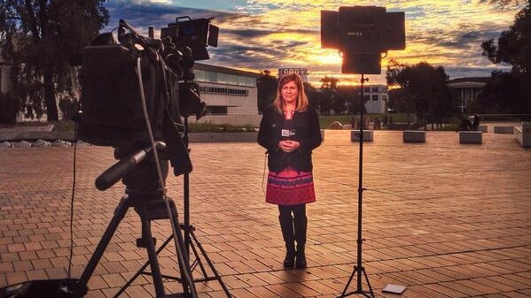 Canberra based High Court reporter Elizabeth Byrne stands in front of a camera holding a microphone.