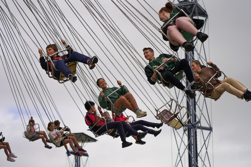 People sit in a carnival ride swing as it spins