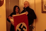 Claudia Patatas holds the pair's son while Adam Thomas holds a swastika flag.