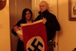 Claudia Patatas holds the pair's son while Adam Thomas holds a swastika flag.