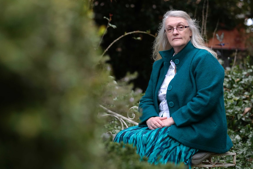 Robyn sits on a bench in her garden.