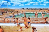 A large swimming pool filled with people with large hills in the background.