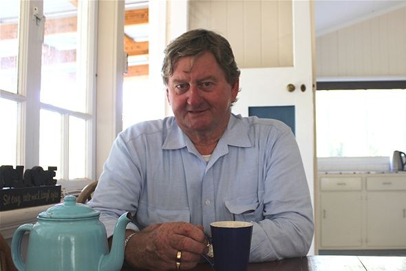 Vaughan Johnson sits in a kitchen with a cup of tea.