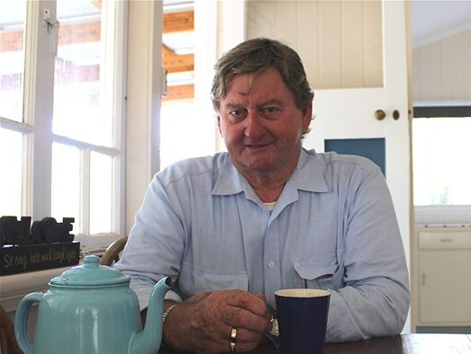 Former Qld politician Vaughan Johnson sitting in his kitchen drinking tea