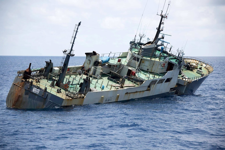 A fishing vessel lists dramatically to the starboard side as it takes on water.