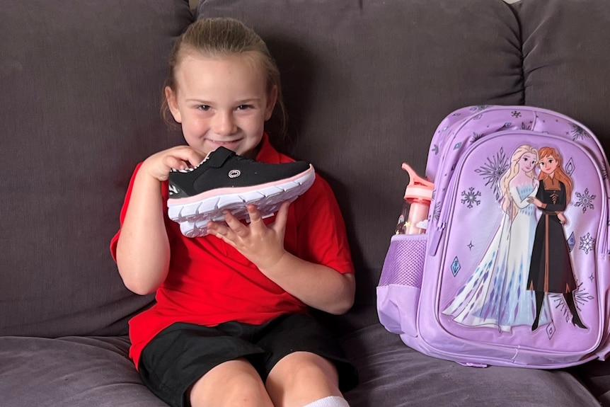 A girl with a new pair of shoes and Frozen-themed backpack.