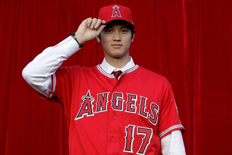 Japanese Los Angeles Angels star Shohei Ohtani tipping his cap in front of a red curtain