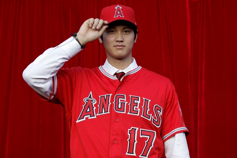 Der japanische Los Angeles Angels-Star Shohei Ohtani kippt seine Mütze vor einem roten Vorhang